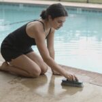 Femme agenouillee brossant piscine exterieure eau claire