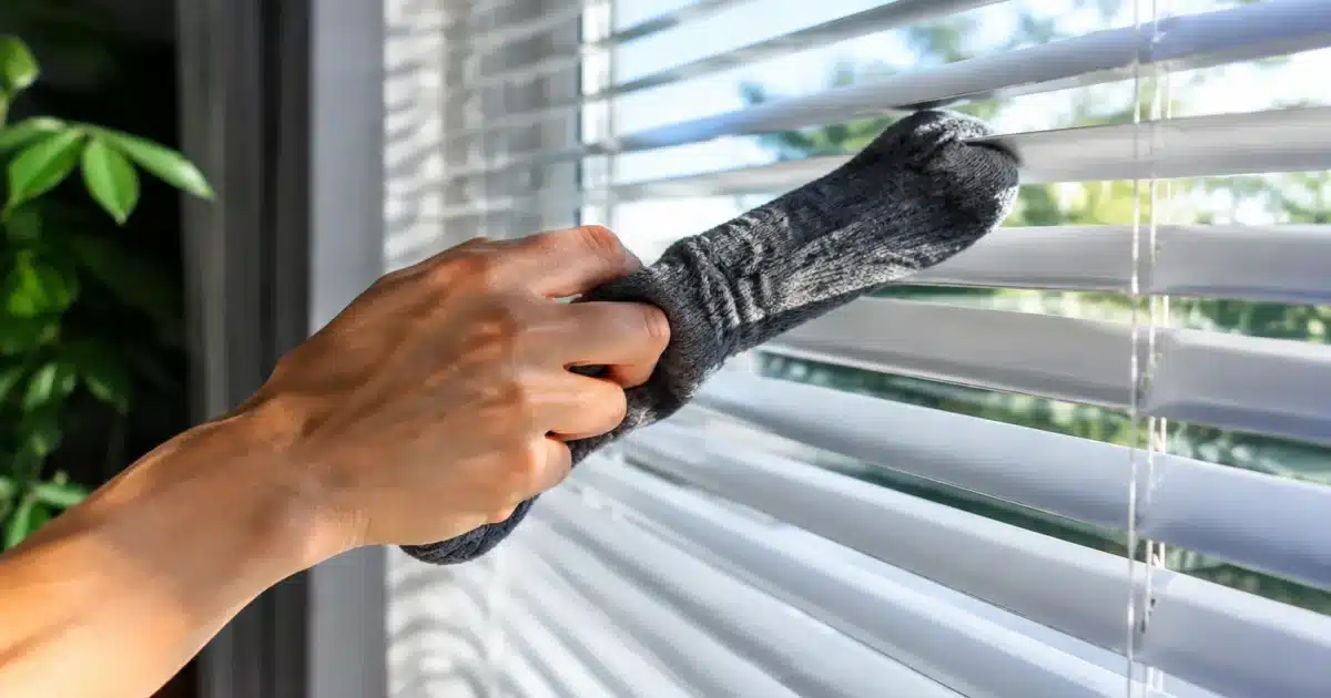 Main enfilant chaussette sur stores horizontaux pour dépoussiérer